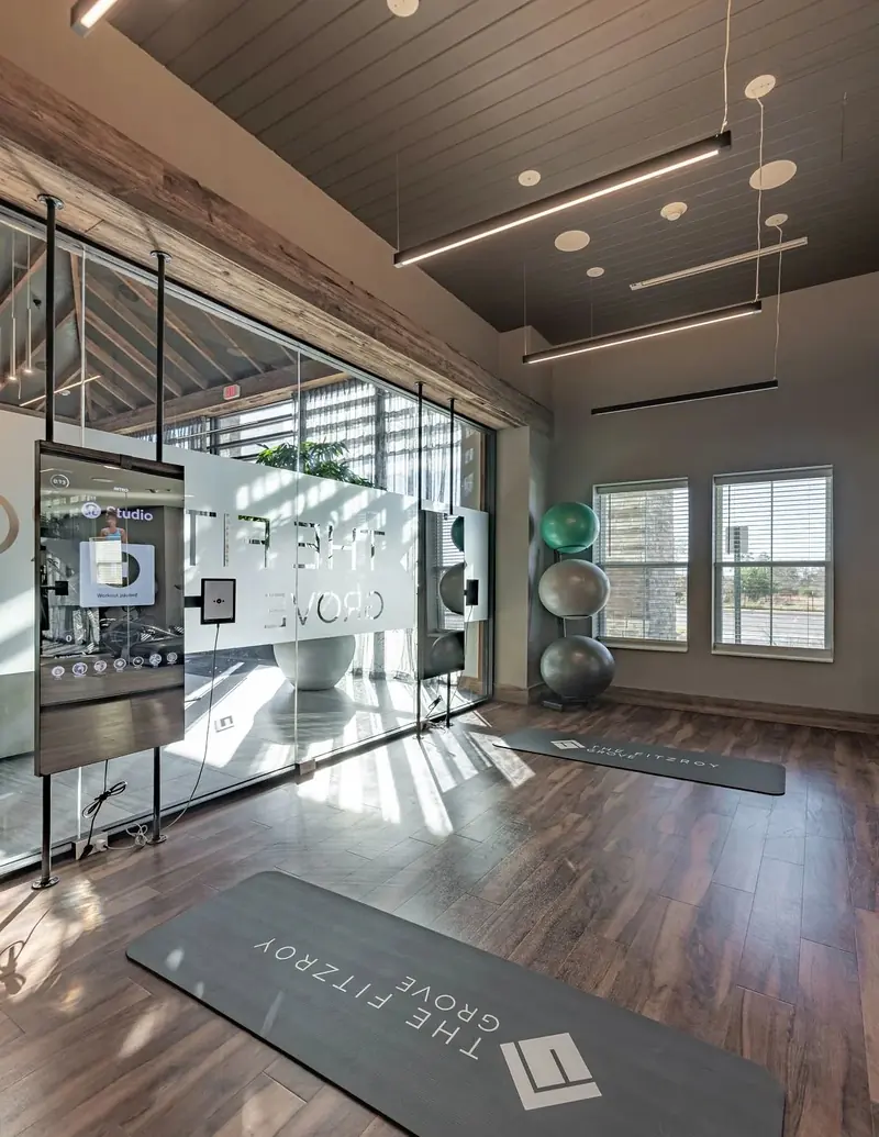 Sunlit fitness studio with branded yoga mats and glass walls