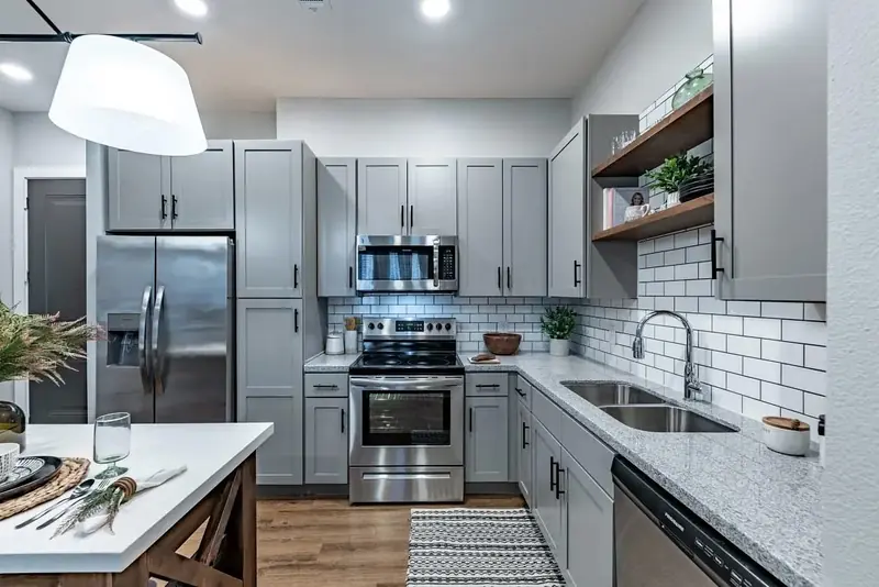 Apartment kitchen with gray shaker cabinets, granite counters and stainless steel appliances