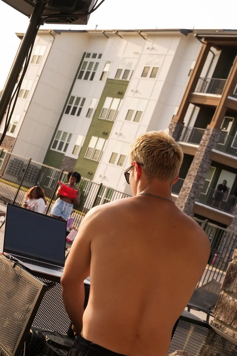 Residents gathering at a summer pool party with the apartment buildings behind